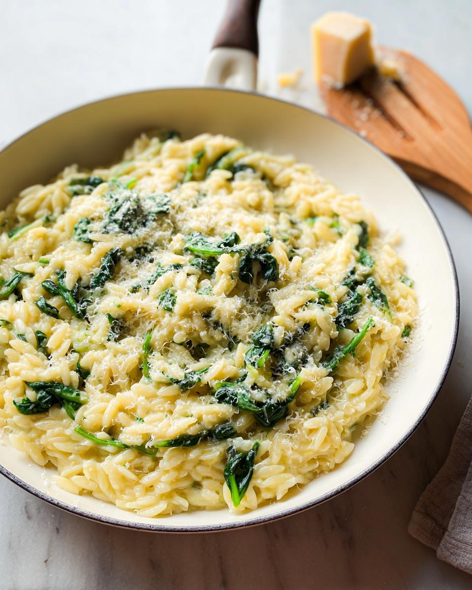 Creamy orzo pasta mixed with wilted spinach and topped with grated Parmesan cheese, a perfect veggie sides recipe.