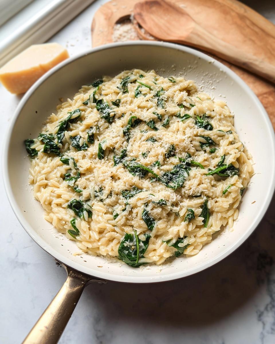 Creamy spinach orzo pasta dish topped with grated Parmesan cheese, a perfect example of veggie sides recipes.