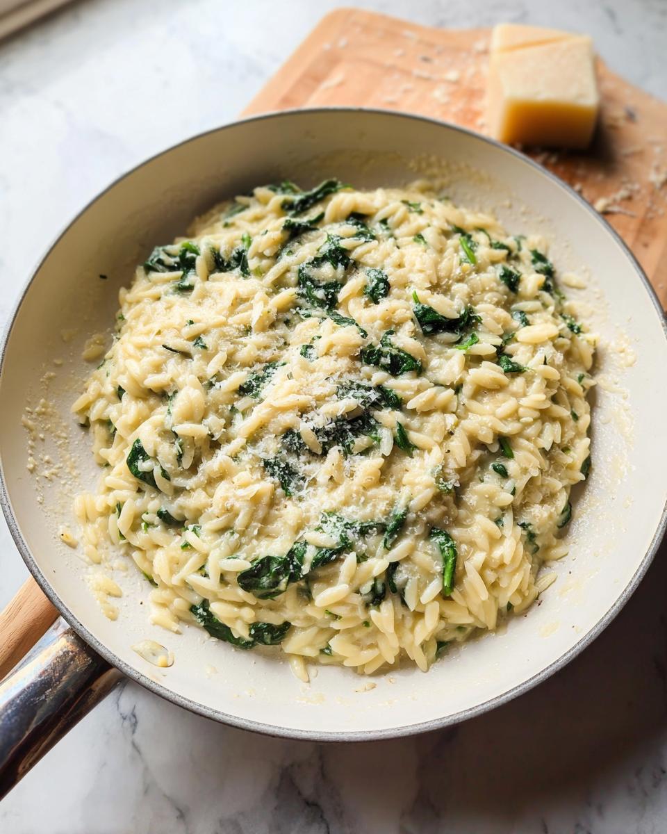 Creamy spinach orzo pasta dish topped with grated Parmesan cheese, a perfect veggie sides recipe.