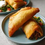 Two crispy, golden-brown fried egg rolls served on a blue plate, part of 20-Ingredient Easy Dinner Recipes.