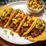 Four delicious tacos filled with shredded meat, topped with mango salsa and cheese, part of 12-Ingredient Taco Tuesday Recipes.