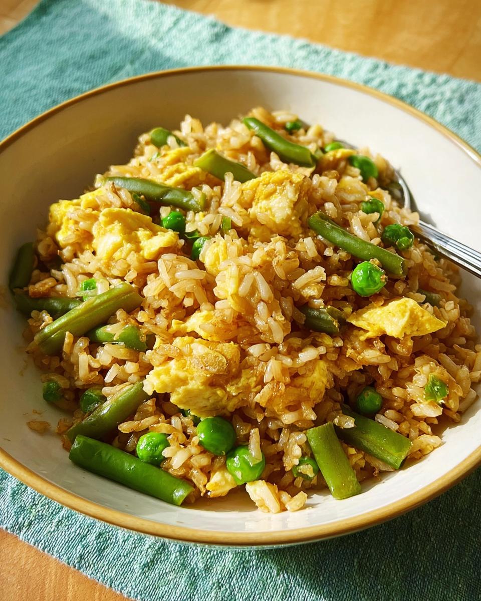 A bowl of simple egg fried rice with green beans and peas, showcasing one of the 7-Ingredient Egg Recipes.