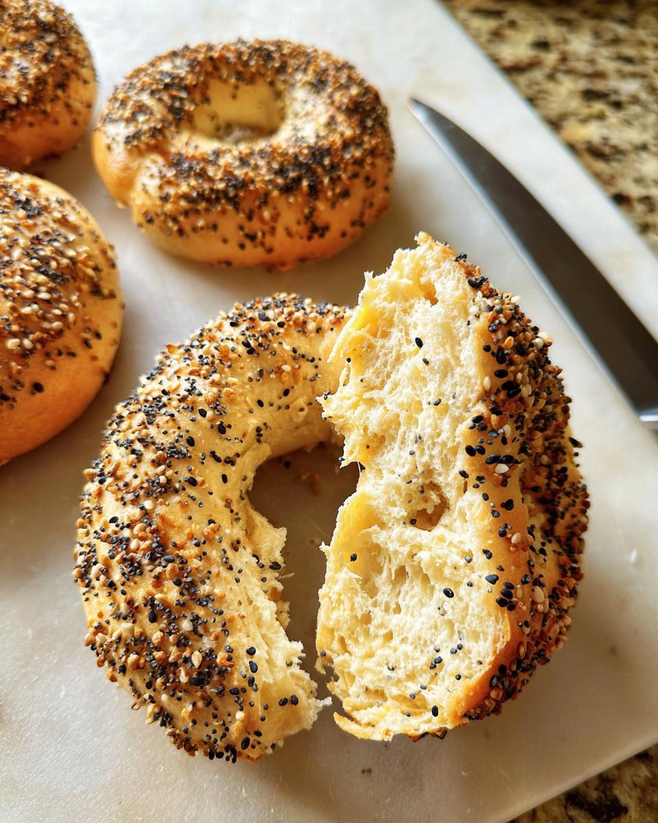 Close-up of an everything bagel torn in half showing the fluffy interior, part of 15 Genius Breakfast Ideas Recipes.