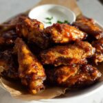 A close-up of saucy, glazed chicken wings piled high on a plate, perfect for quick Chicken Wings Recipes in 20 Minutes.