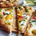 Slices of gourmet pizza topped with pesto, mozzarella, fresh basil, and sliced peaches, ready for Pizza Night Recipes.