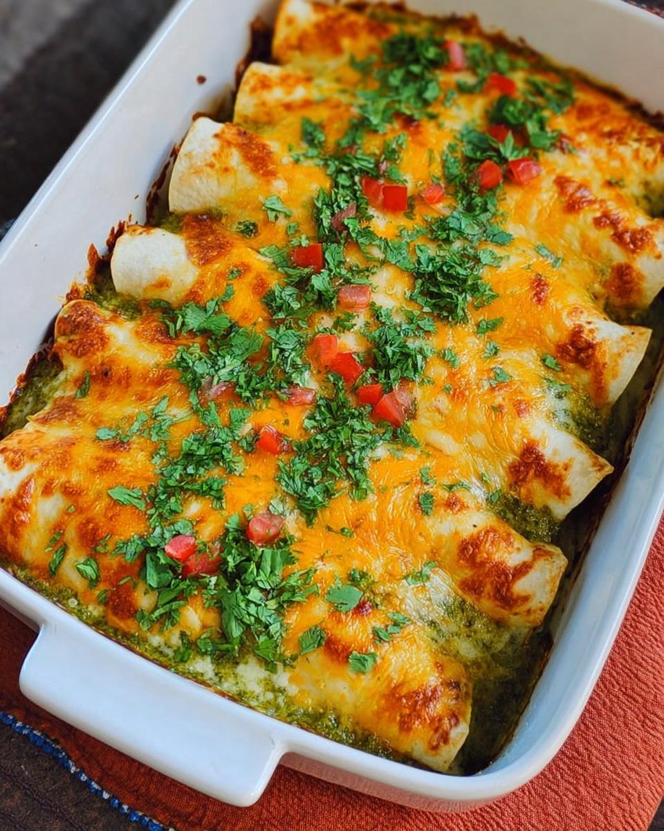 Baked green chicken enchiladas covered in melted cheddar cheese, cilantro, and diced tomatoes.