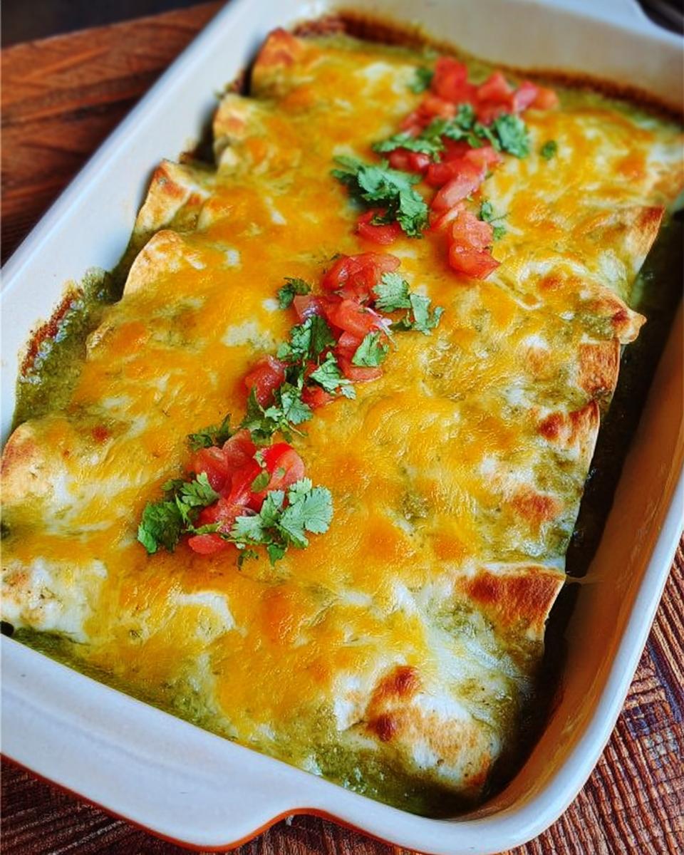 Close-up of green chile chicken enchiladas covered in melted cheese and topped with diced tomatoes and cilantro.