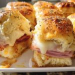 Close-up of baked ham and cheese sliders topped with poppy seeds, perfect for busy weeknight sandwich ideas.