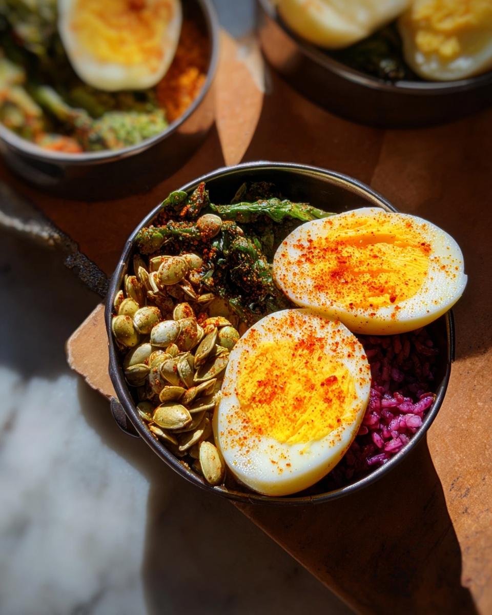 Close-up of a breakfast bowl featuring hard-boiled eggs, seasoned pumpkin seeds, and greens, part of The Ultimate Egg Recipes Guide.