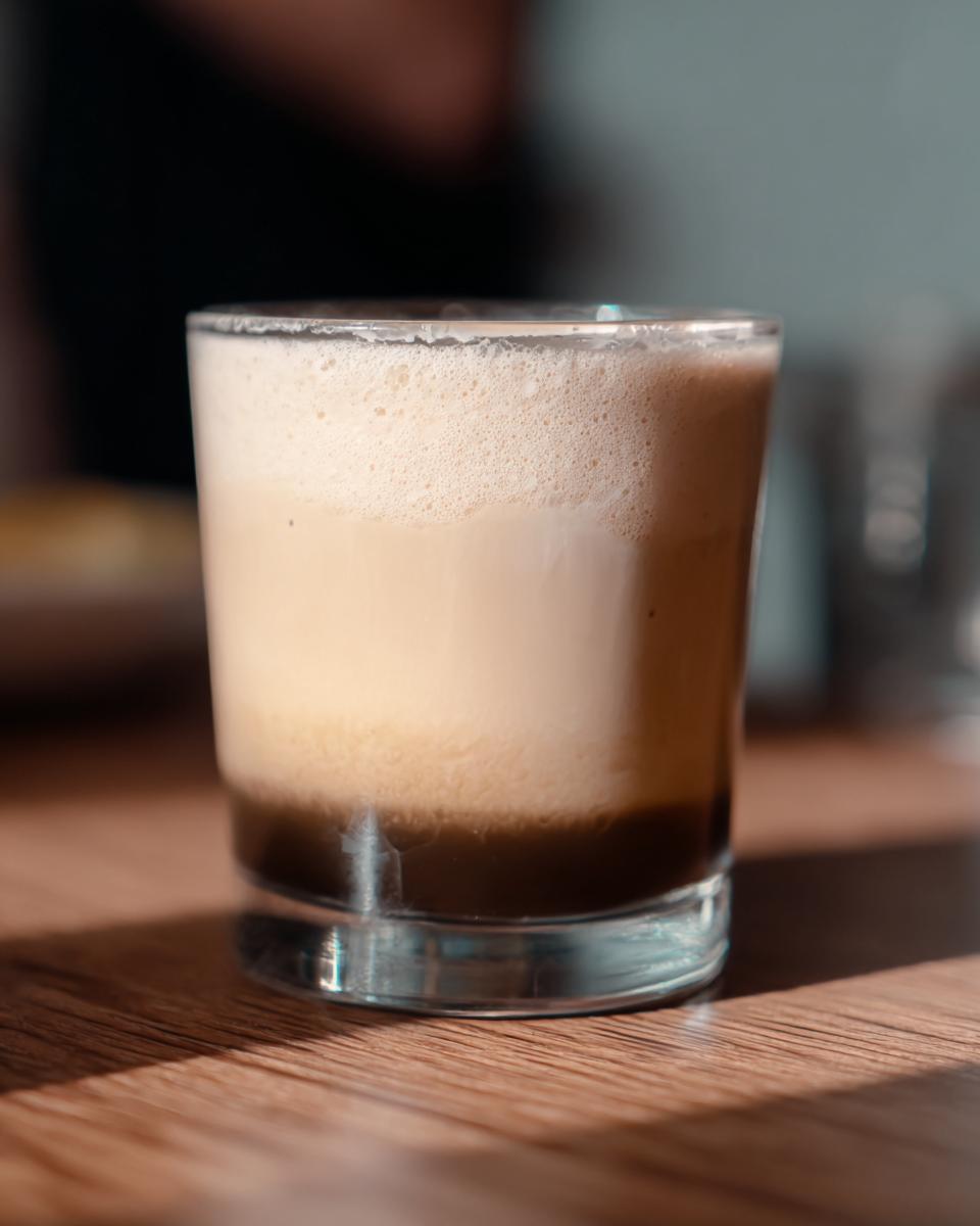 Close-up of a layered iced coffee drink with a dark base and creamy foam top, perfect for Starbucks drinks recipes ideas.