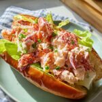 A close-up of a creamy lobster roll served on a toasted bun with lettuce, a great sandwich idea.
