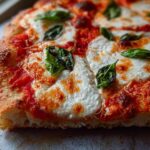 A close-up, cross-section view of a freshly baked Margherita pizza, highlighting the bubbly crust, melted mozzarella, and fresh basil for Pizza Night Recipes.