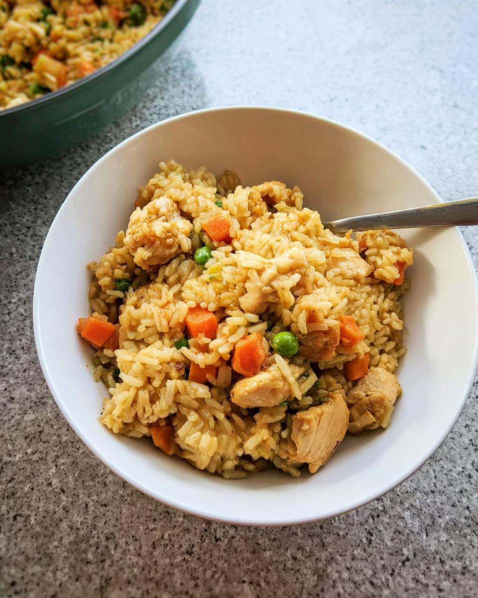 A white bowl filled with quick chicken fried rice featuring carrots and peas, part of our Rice Bowls Recipes in 12 Minutes.