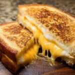 Close-up of a perfectly grilled sandwich cut in half, showing melted cheese oozing out for a classic Restaurant-Style Grilled Cheese.
