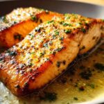 Two perfectly cooked fillets of Restaurant-Style Salmon Recipes at Home glistening in a garlic butter sauce with fresh parsley.