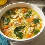 Close-up of a bowl of homemade chicken orzo soup with carrots and spinach, perfect for Restaurant-Style Soup Recipes at Home.