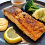 A beautifully seared salmon fillet served with a lemon wedge and steamed vegetables, part of 12-Ingredient Salmon Recipes.