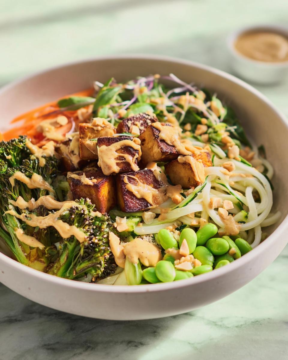 Close-up of a vibrant rice bowl featuring tofu, roasted broccoli, edamame, and peanut sauce, part of 20-Ingredient Rice Bowls Recipes.