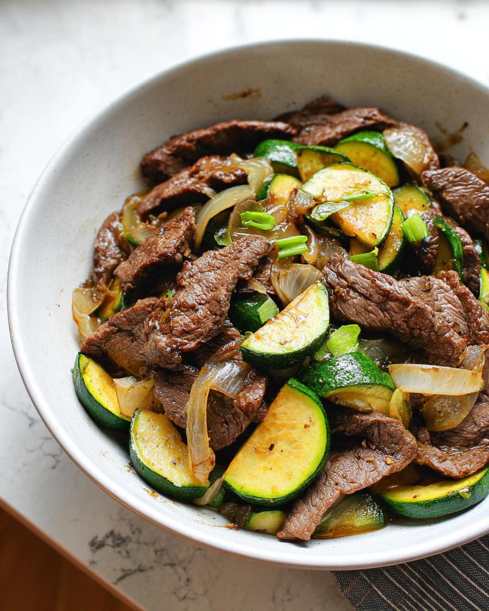 Close-up of the Cozy Grilled Steak Bowl with Zucchini, featuring sliced steak, zucchini, and onions.