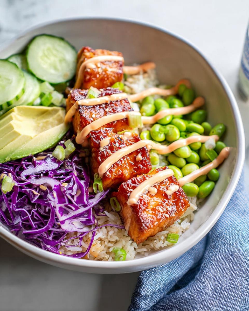 Close-up of a Crispy Salmon and Rice Bowl featuring glazed salmon cubes, rice, edamame, avocado, and purple cabbage.