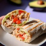A halved Easy Chipotle Ranch Grilled Chicken Burrito showing grilled chicken, lettuce, tomatoes, and creamy sauce inside a toasted tortilla.