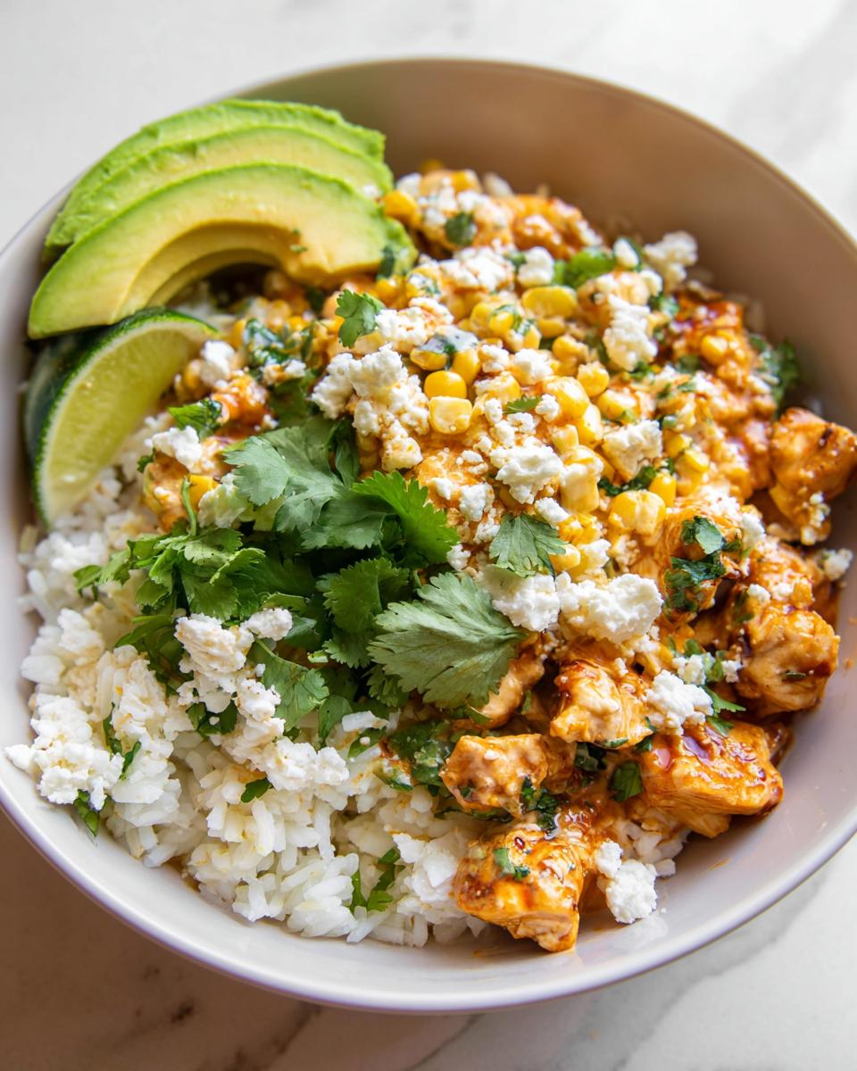 Close-up of an Easy Street Corn Chicken Bowl featuring seasoned chicken, rice, corn, cotija cheese, and avocado slices.