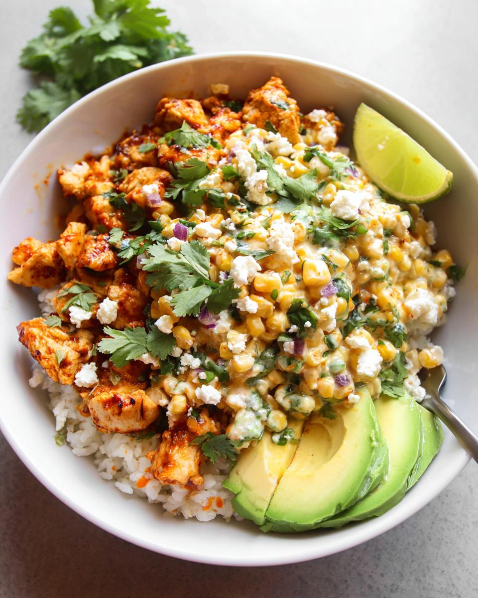 A close-up of an Easy Street Corn Chicken Bowl featuring seasoned chicken, creamy corn salad, avocado, and cilantro.