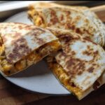 Close-up of golden brown High-Protein Chicken Ranch Quesadilla slices filled with melted cheese and chicken on a plate.