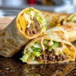 Close-up of Homemade Big Mac Wraps cut in half, showing ground beef, lettuce, cheese, pickles, and special sauce.