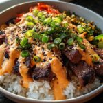 Close-up of Korean BBQ Steak Rice Bowls topped with spicy cream sauce, scallions, and sesame seeds.
