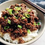 Close-up of a Korean Ground Beef Bowl featuring savory ground beef over white rice, topped with sesame seeds and green onions.