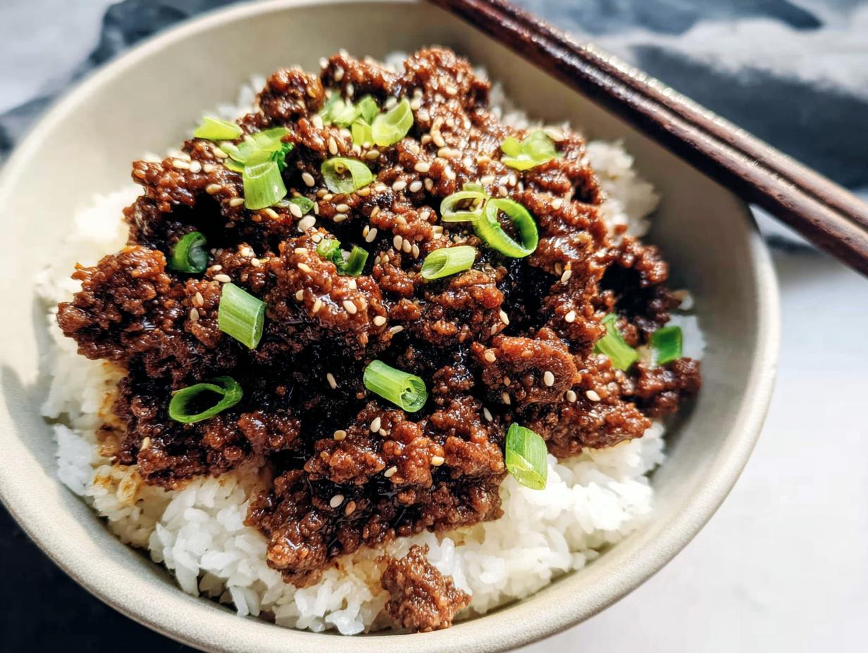 Close-up of a Korean Ground Beef Bowl featuring savory ground beef over white rice, topped with sesame seeds and green onions.