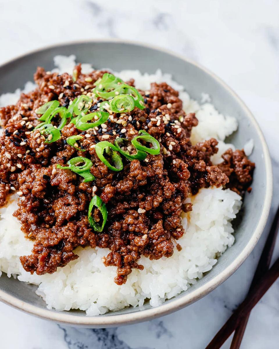Close-up of a delicious Korean Ground Beef Bowl featuring savory ground beef over white rice, garnished with green onions and sesame seeds.