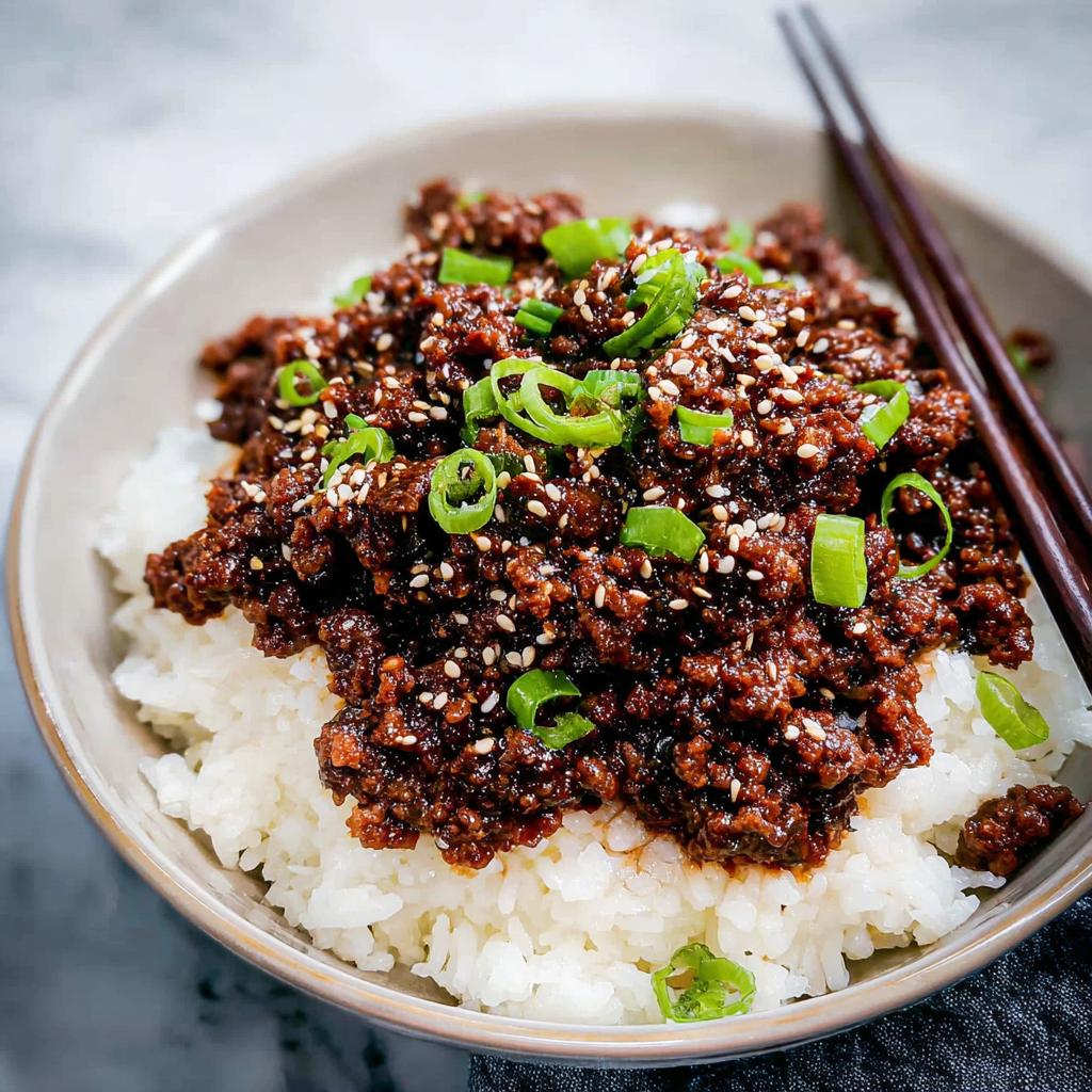 A close-up of a Korean Ground Beef Bowl served over white rice, topped with sesame seeds and sliced green onions.