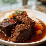 Close-up of tender Korean Style Pot Roast pieces covered in rich, dark sauce served over white rice.