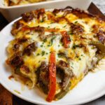 A generous slice of Low Carb Philly Cheesesteak Casserole topped with melted cheese, steak, and peppers.