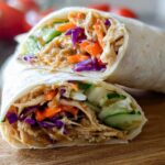 Cross-section of a Teriyaki Chicken Wrap Recipe showing shredded chicken coated in sauce, mixed with shredded carrots, red cabbage, and cucumber slices.