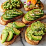 A spread of various avocado toast options, showcasing sliced and mashed avocado on toasted bread with seasonings.