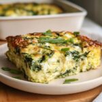 A slice of Baked Cottage Cheese Eggs with spinach and feta, garnished with chives, on a plate.