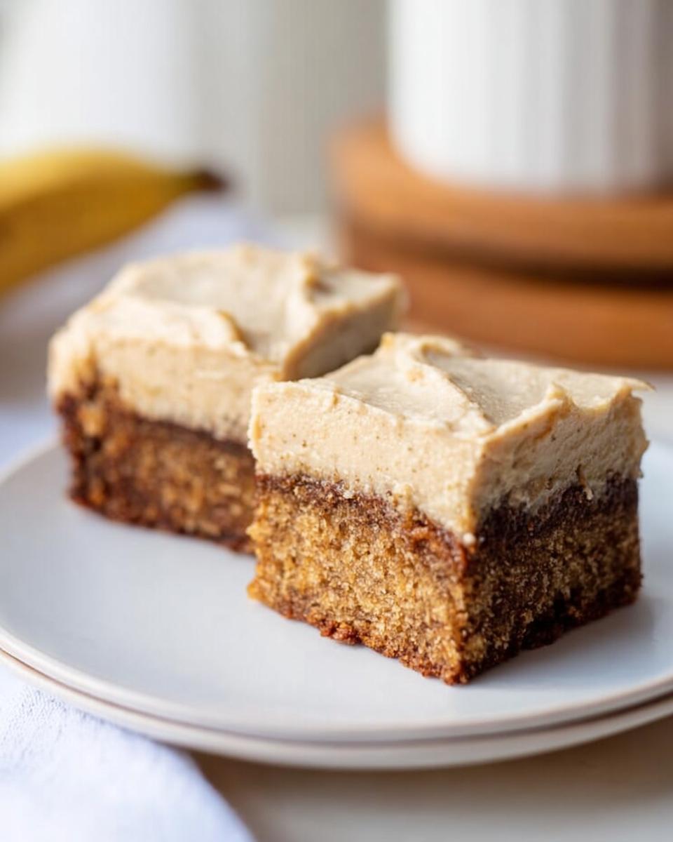 Two delicious slices of Banana Bread Brownies Made Easy, topped with creamy frosting, on a white plate.