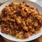 A close-up shot of a white plate filled with savory BBQ Chicken and Rice, featuring tender chicken pieces mixed with fluffy rice.