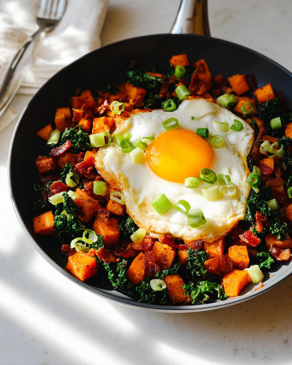 A savory one-pan BREAKFAST SWEET POTATO hash topped with a fried egg, bacon, and green onions.