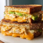 A stacked Chicken Avocado Melt Sandwich with gooey melted cheese and fresh avocado slices.