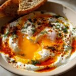 Close-up of Çılbır: Turkish Eggs with Creamy Yogurt & Butter Sauce, featuring runny egg yolks, creamy yogurt, and a drizzle of spiced butter.