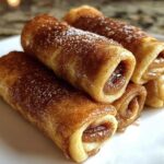 Close-up of delicious Cinnamon Roll French Toast Roll-Ups dusted with powdered sugar and cinnamon.