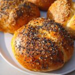 A close-up of four golden-brown cottage cheese flagels topped with various seeds, ready to be enjoyed.