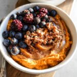 A Delicious Sweet Potato Breakfast Bowl topped with fresh blueberries, raspberries, and chopped nuts.