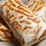 Close-up of two Easy Chipotle Ranch Grilled Chicken Burritos, showing the golden-brown tortilla and visible filling of chicken, corn, and sauce.