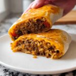 A close-up of a Grilled Cheese Burrito Made Easy, cut in half, revealing seasoned ground beef and rice filling with melted cheese.