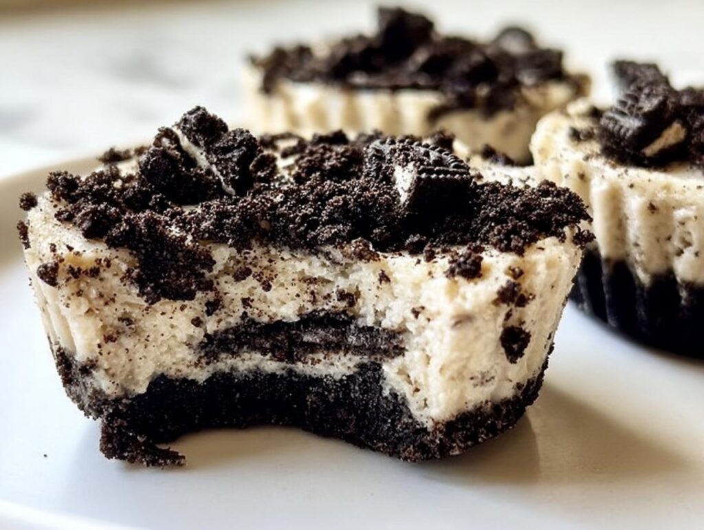 Close-up of a Healthy No-Bake Oreo Cheesecake Bite with a bite taken out, showing layers of cream cheese and crushed Oreos.